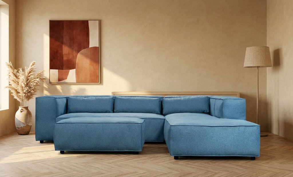 Canapé Genua en tissu bleu pétrole dans un salon aux murs couleur sable – mise en situation