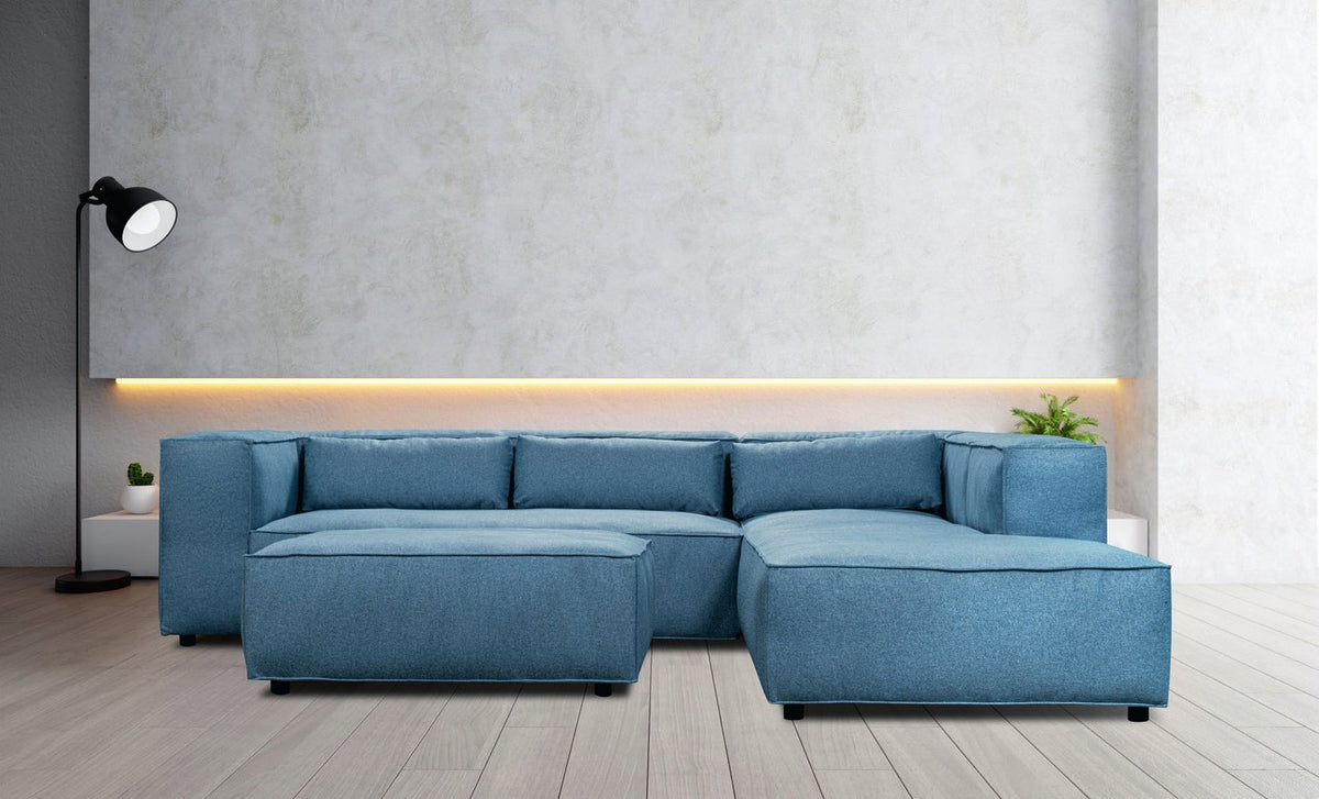 Canapé d'angle Genua en tissu bleu pétrole, lignes cubiques et assise basse, dans un salon au mur clair
