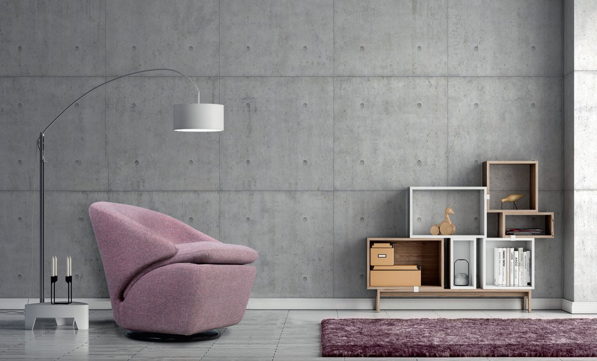 Fauteuil cocon Birdy en tissu rose poudré sur pied central en métal, dans un salon au mur de béton